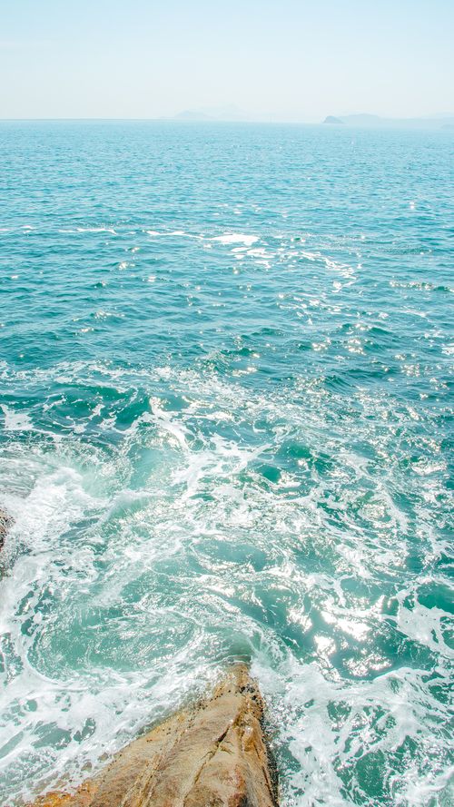 Free Scenic view of sparkling blue ocean waves crashing against rocks in bright daylight. Stock Photo