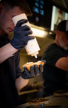 Chef adding sauce to a gourmet burger at a Berlin food truck, emphasizing street culinary craftsmanship.