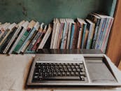 在家庭环境中，一台复古的德州仪器电脑被各种书籍环绕，展示了技术与文学的融合