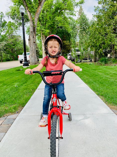 Photo Of Young Girl Riding Bike By Sidewalk Free Stock Photo