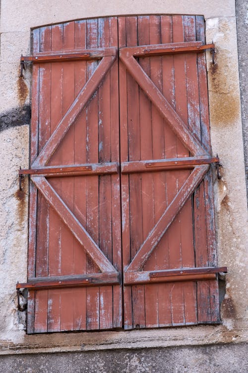 A red wooden shutter with a rusty metal frame