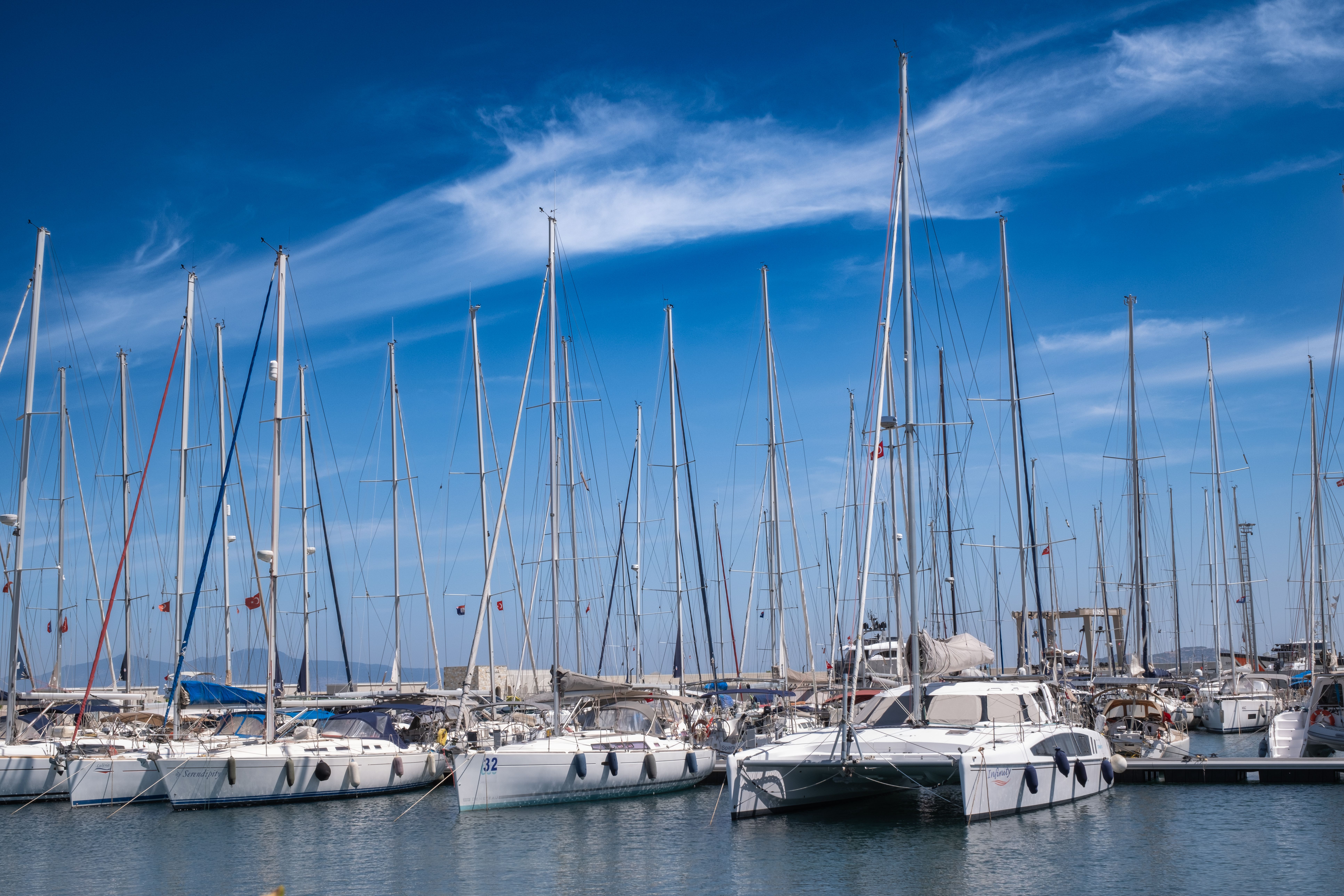 Sarasota 63’ Peace Prestige 630 | 8hr Private Yacht Charter - Sailboats and yachts moored at a scenic marina in Foça, İzmir on a sunny day.