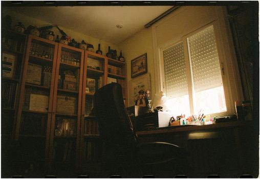 A dimly lit home office with a bookshelf and window, creating a serene work environment.