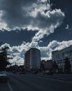城市街道与高楼大厦在戏剧性的多云天空下，车辆穿行其间