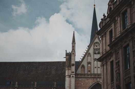 在多云的天空下，布鲁塞尔历史悠久的哥特式大教堂从低视角展现了复杂的建筑细节