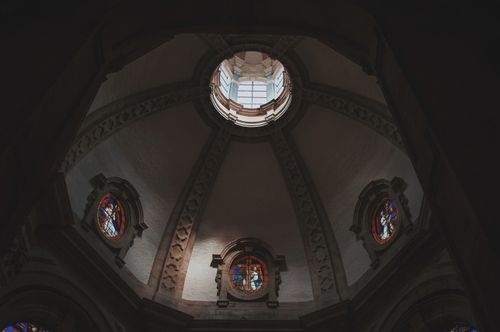 Free Dramatic low angle shot of a church dome interior showcasing intricate stained glass windows and architectural details. Stock Photo