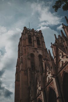 在多云的天空下，从低角度拍摄的哥特式大教堂塔楼显得格外富有戏剧性