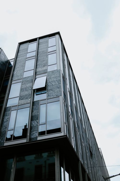 Free Low angle view of a modern building with glass facade under a cloudy sky. Stock Photo