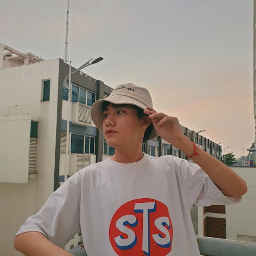 Photo of Man in White T-shirt and Bucket Hat Posing While Looking Away