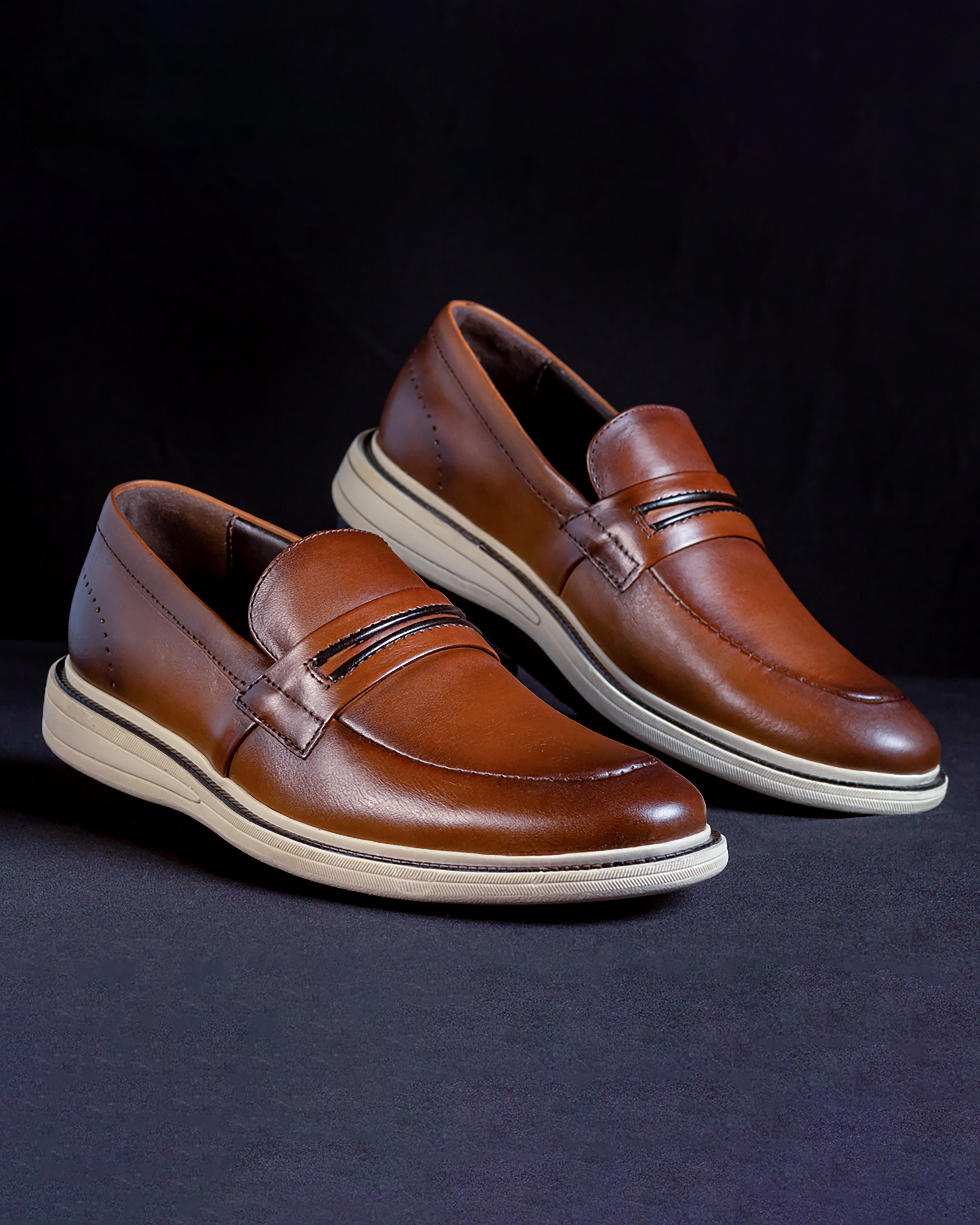 Stylish brown leather loafers displayed against a black backdrop for fashion-focused photography.