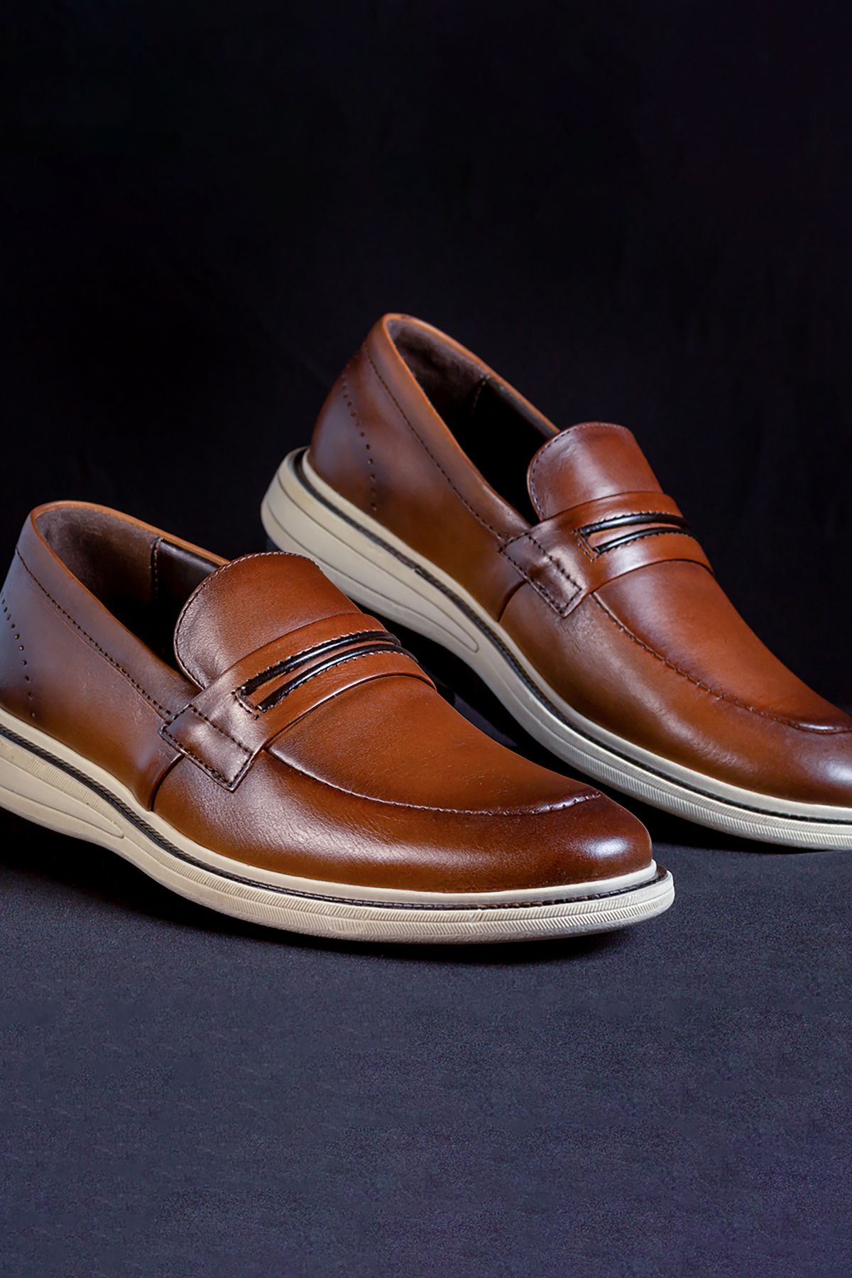 Oslo penny loafer in cognac leather on a dark ground