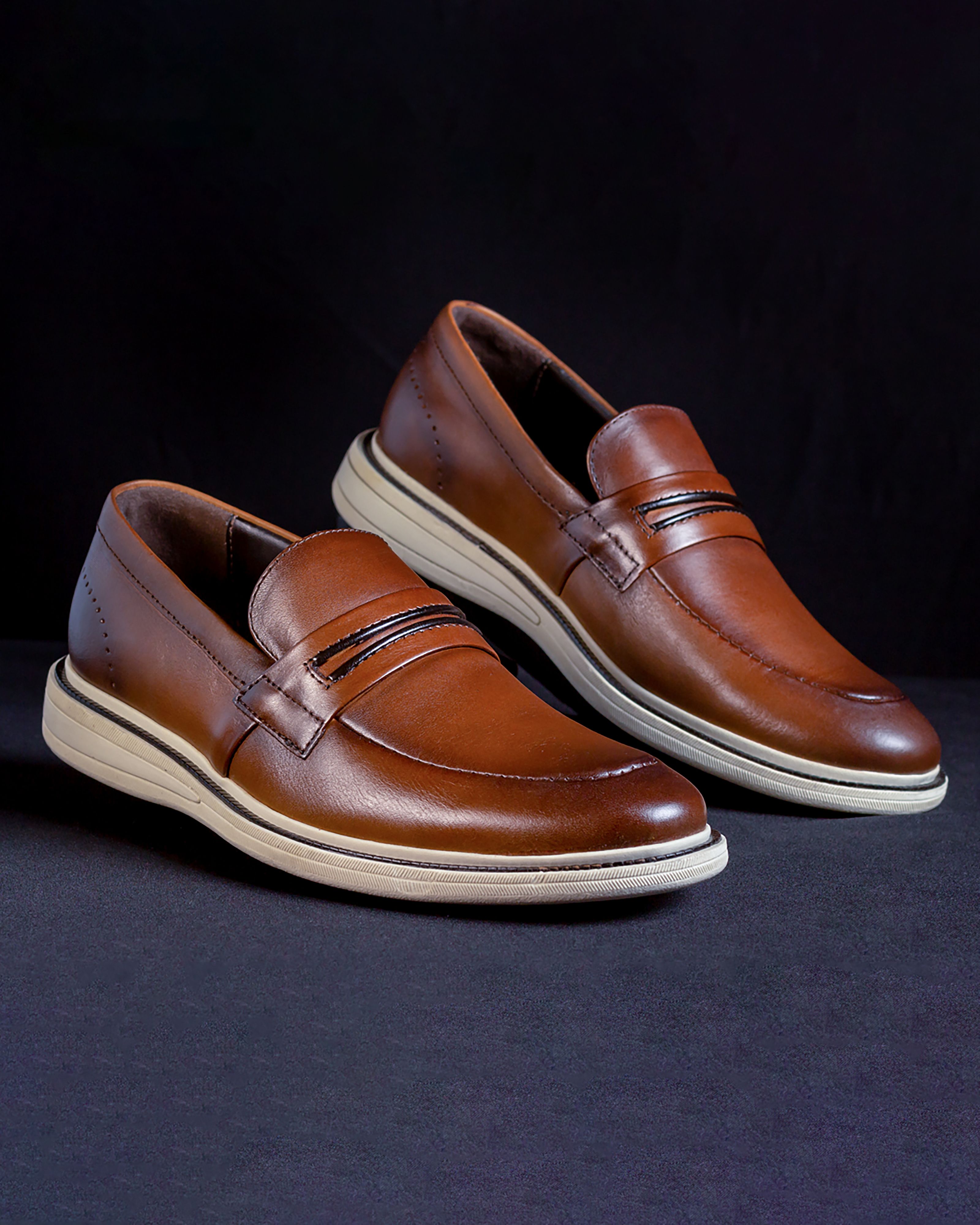 Mocassins de couro marrom estilosos exibidos contra um fundo preto para fotografia voltada à moda.