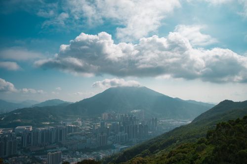Free Breathtaking view of Shenzhen city skyline surrounded by lush green mountains and dramatic clouds. Stock Photo