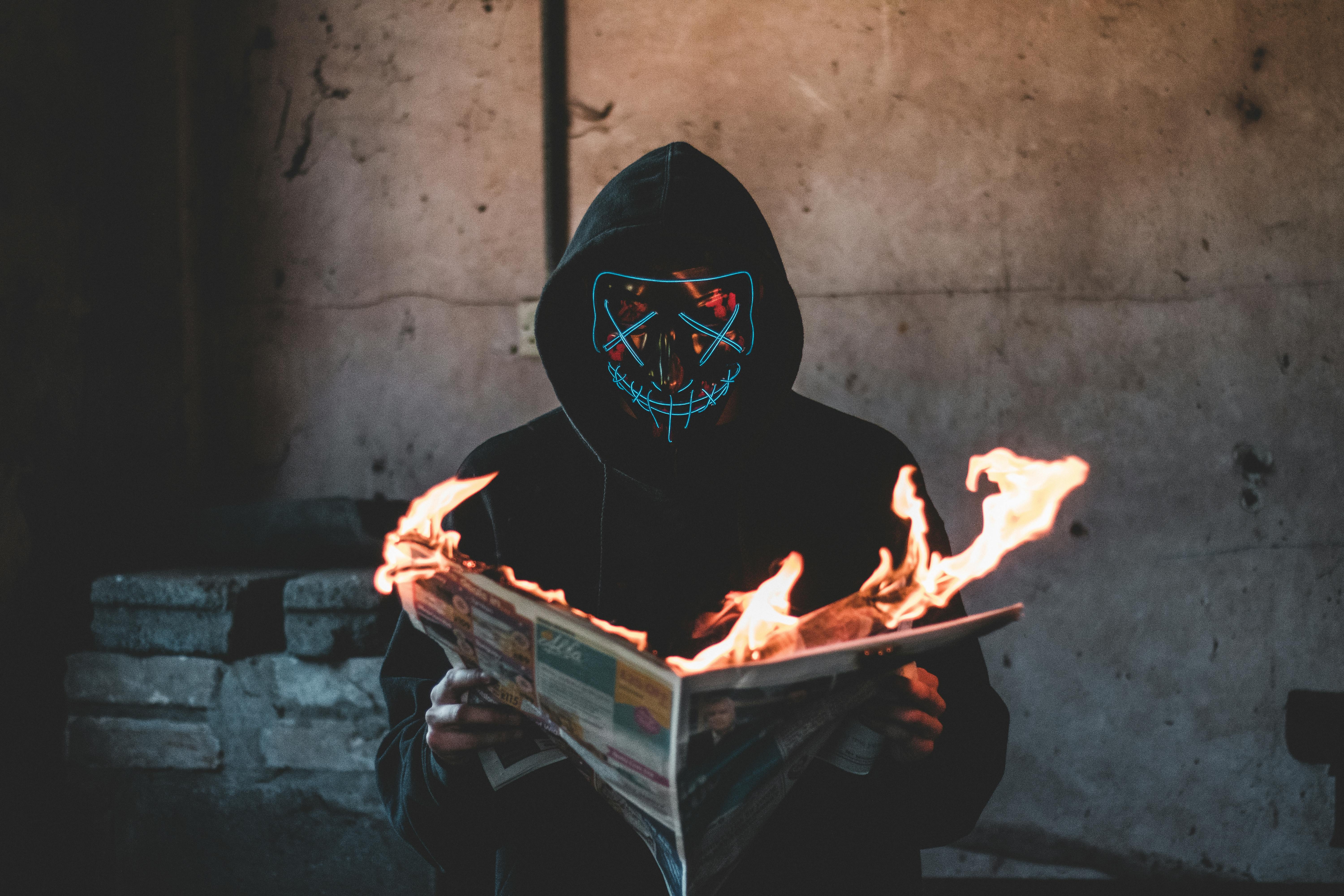 hård Morgen knude Person with Black Mask holding a Burning News Paper · Free Stock Photo