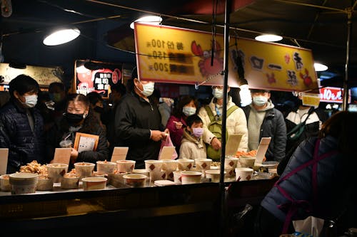 People in masks at a food stand in a market
