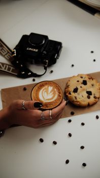 Stylish arrangement of coffee, cookie, and vintage camera on a table with artistic coffee art.