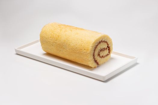 Close-up of a tasty Swiss roll cake on a white plate, perfect for dessert lovers.