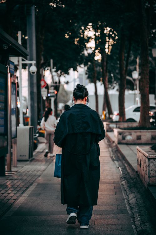 Free Back view of a person walking on Shenzhen city streets, capturing urban lifestyle and evening ambiance. Stock Photo