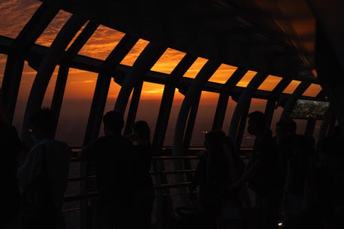 People are standing on a bridge looking at the sunset