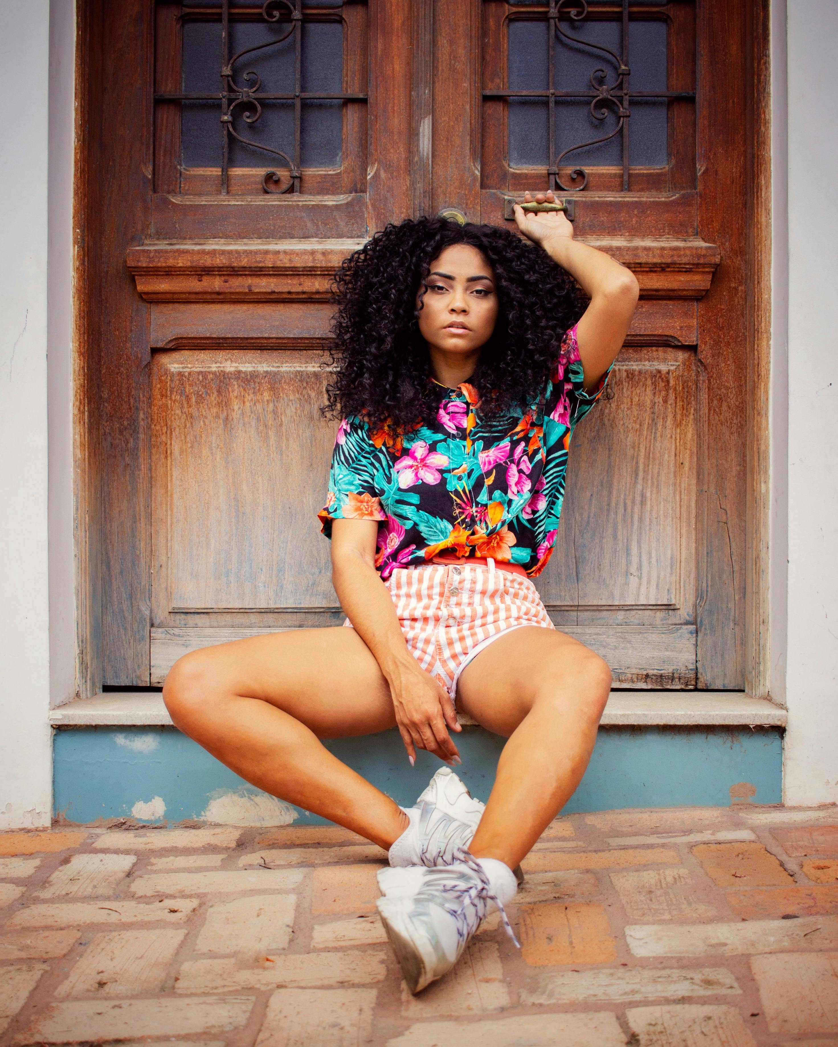 Fashionable woman in vibrant clothing posing against a wooden door, exuding confidence and style.