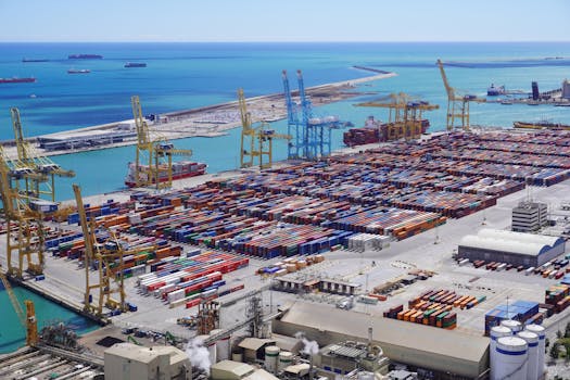 Dynamic aerial view of shipping containers and cranes in Barcelona port handling logistics.