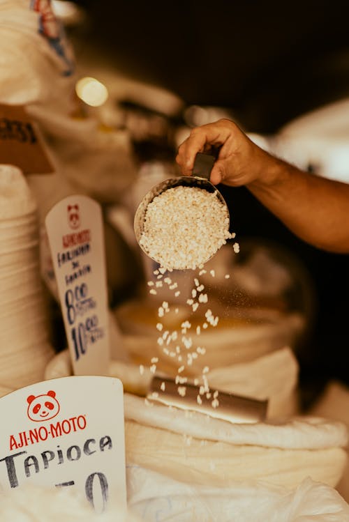 A person is holding a bag of rice in front of a table