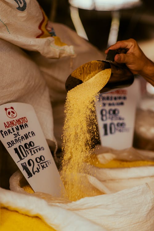 A person pouring yellow rice into a bag