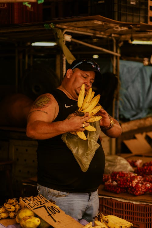 A man with tattoos and a tattoo on his arm is holding bananas