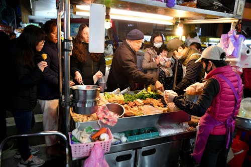 A group of people standing around a food stand