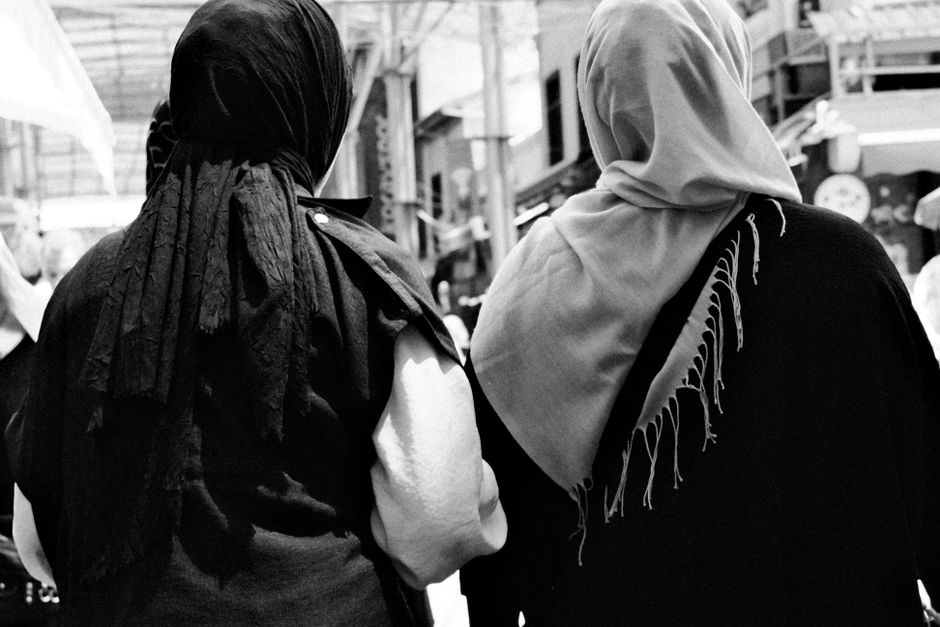 Women respectfully wearing headscarves and modest clothing entering a mosque in Turkey