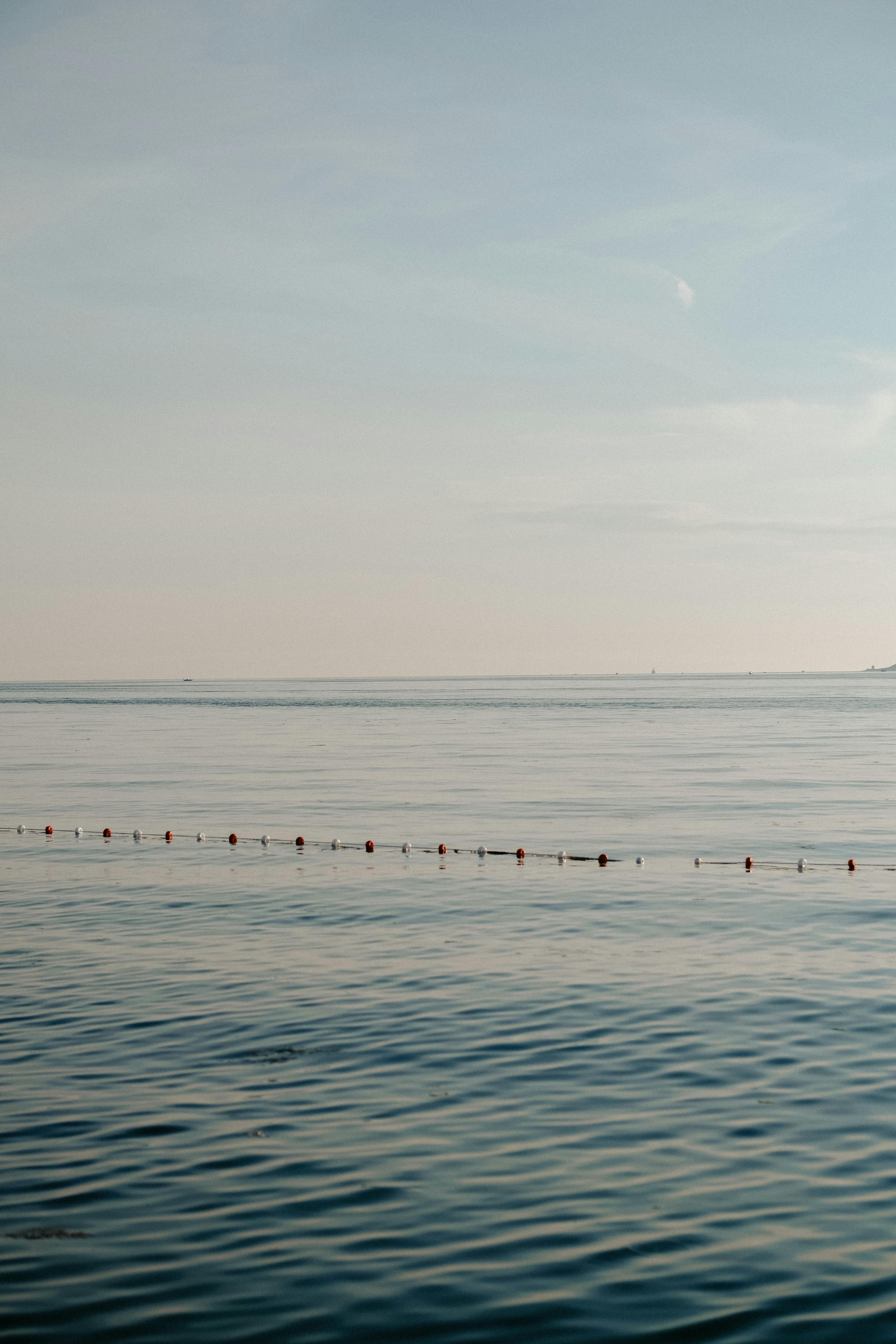 A tranquil seascape with a calm ocean and a clear blue sky.