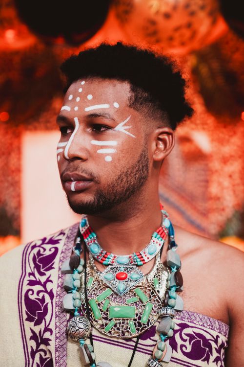Free Portrait of a man in traditional tribal attire and face paint, vibrant setting. Stock Photo