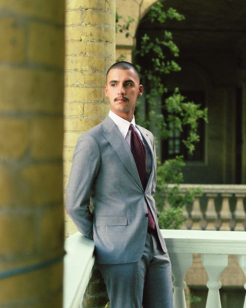 Free Stylish man with mustache in a gray suit posing outdoors against a picturesque background. Stock Photo