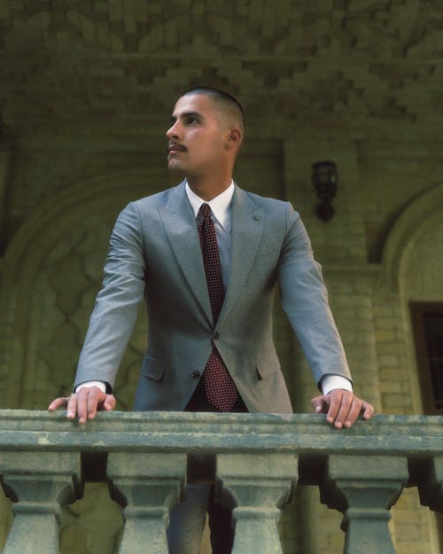 A man in a suit leaning on a balcony
