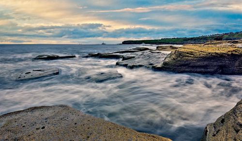 Free Calm and serene coastal scene with waves gently lapping against rocky shore under a twilight sky. Stock Photo
