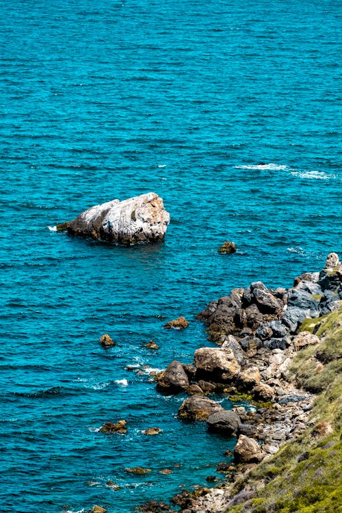 A rock in the ocean near a rocky shore