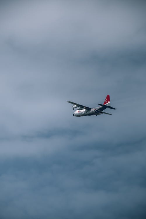 A small plane flying in the sky with a cloudy sky
