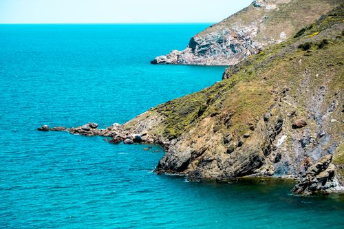 Free A stunning rocky coastline meets turquoise sea under a clear daytime sky. Stock Photo