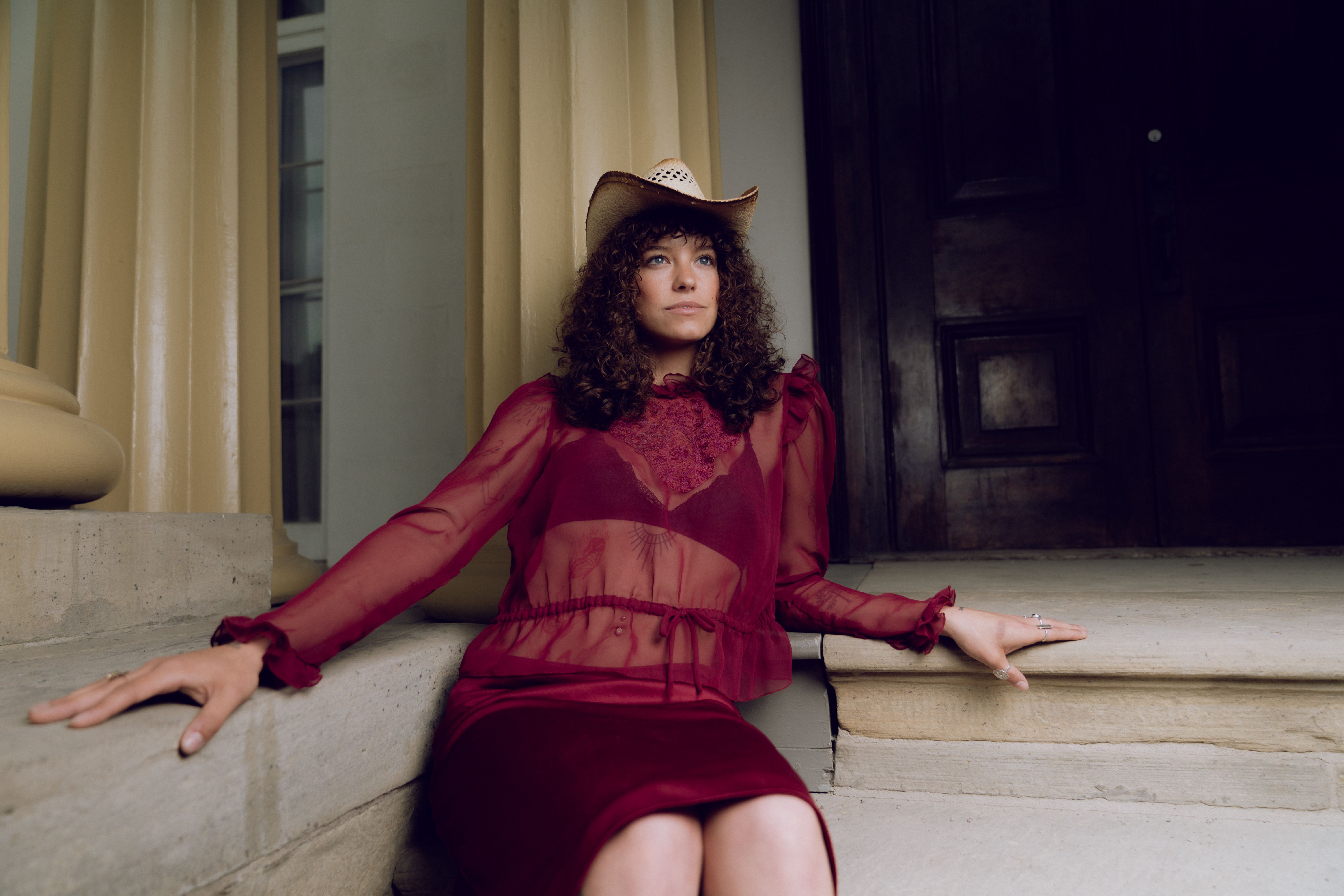 A woman in a red dress and hat sitting on steps · Free Stock Photo