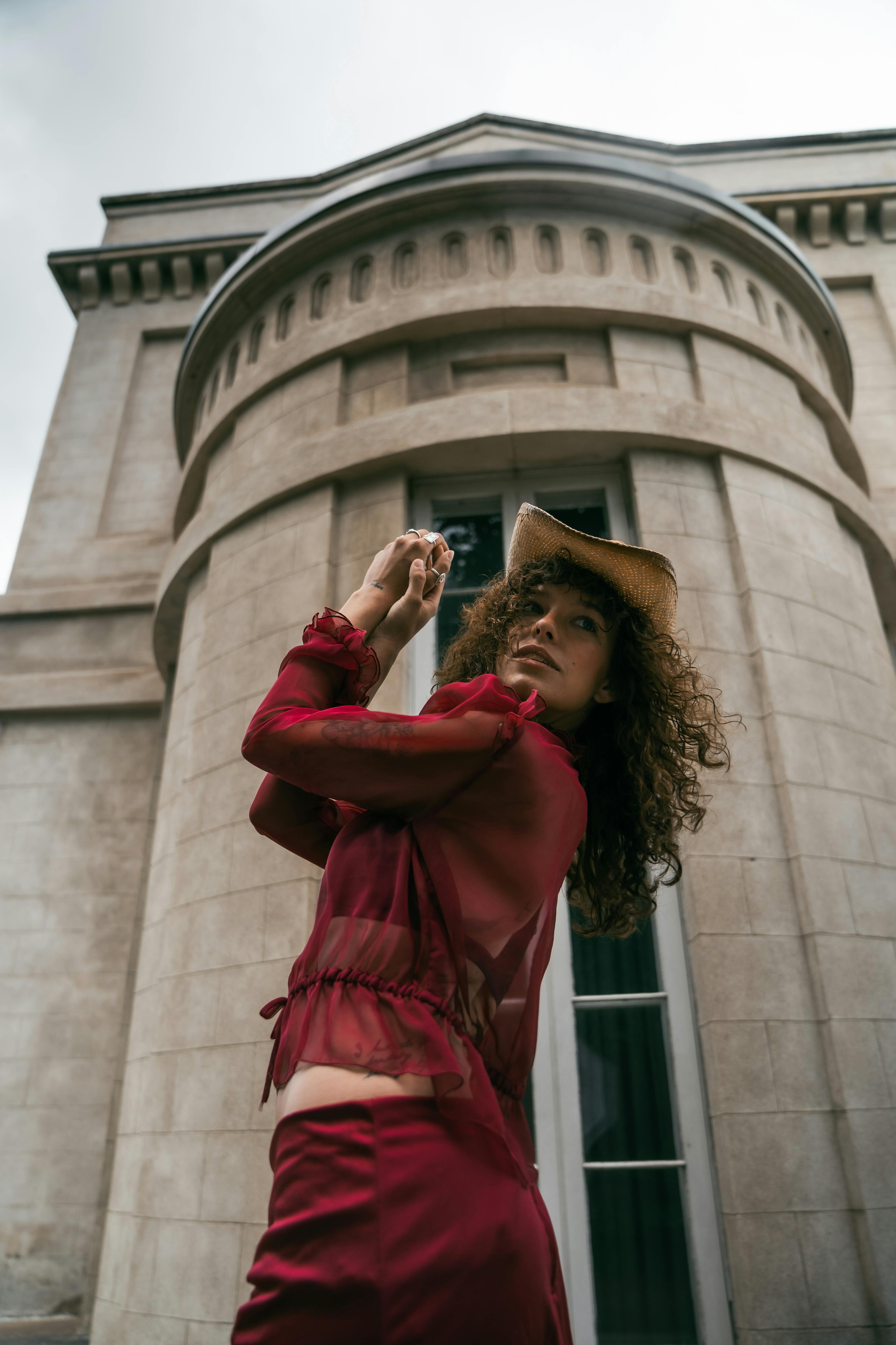 a woman in a red dress is standing in front of a building