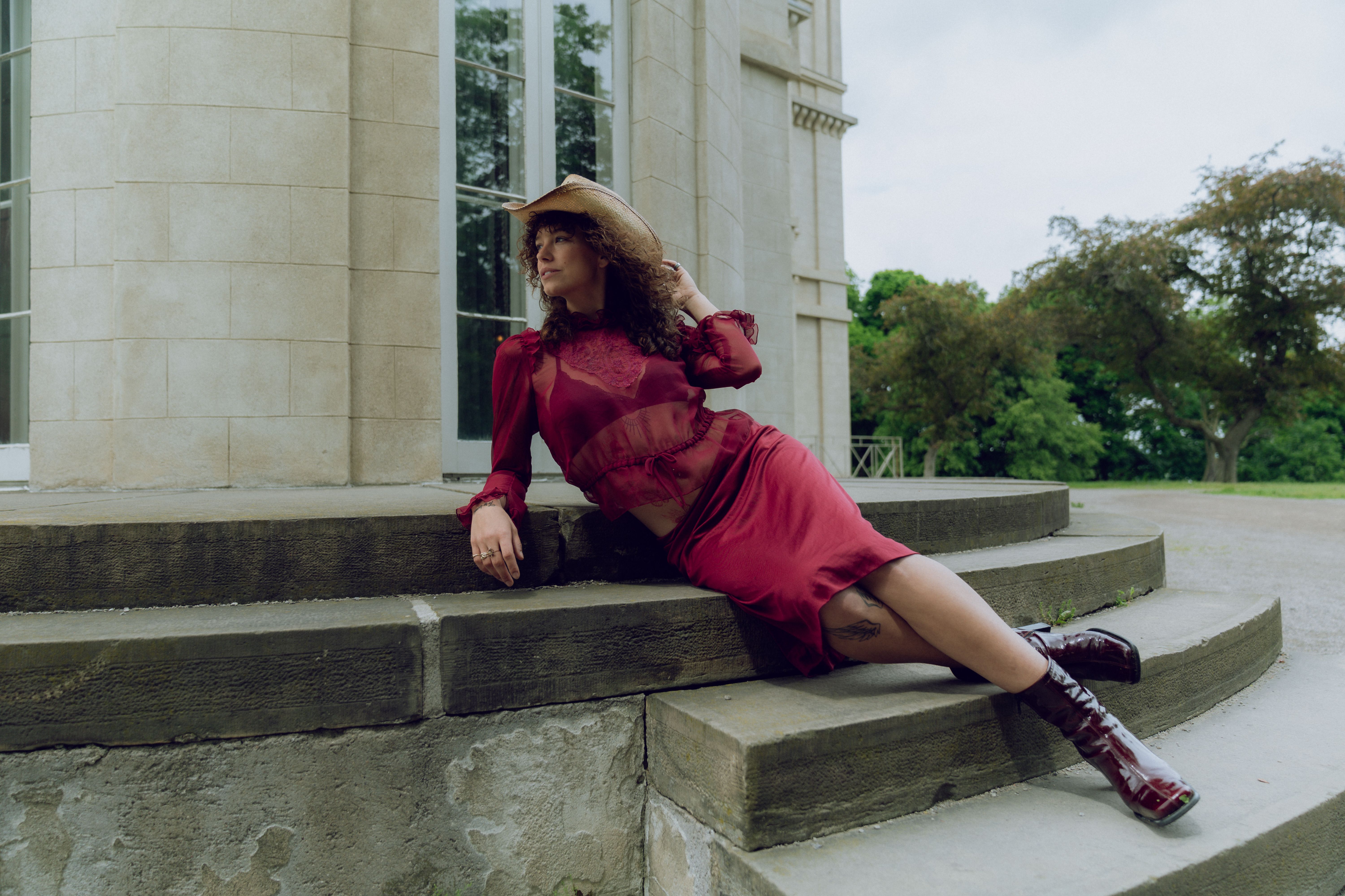 A woman in a red dress and hat sitting on steps · Free Stock Photo
