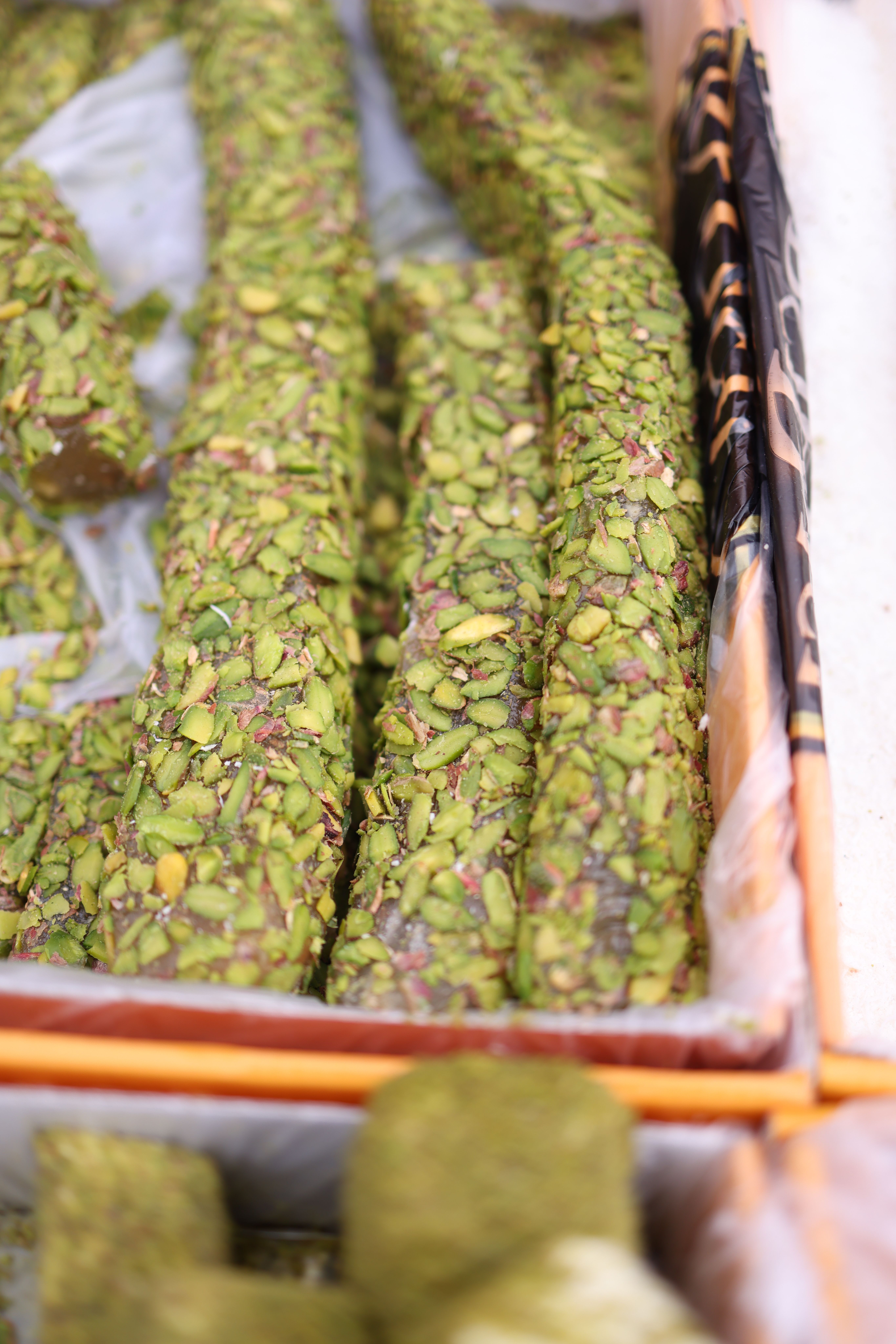Detailed shot of pistachio-covered Turkish delight, showcased in a market setting.