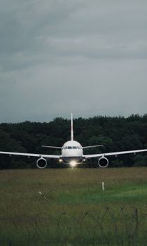 A commercial airplane approaches for landing at Geneva Airport against a cloudy sky.