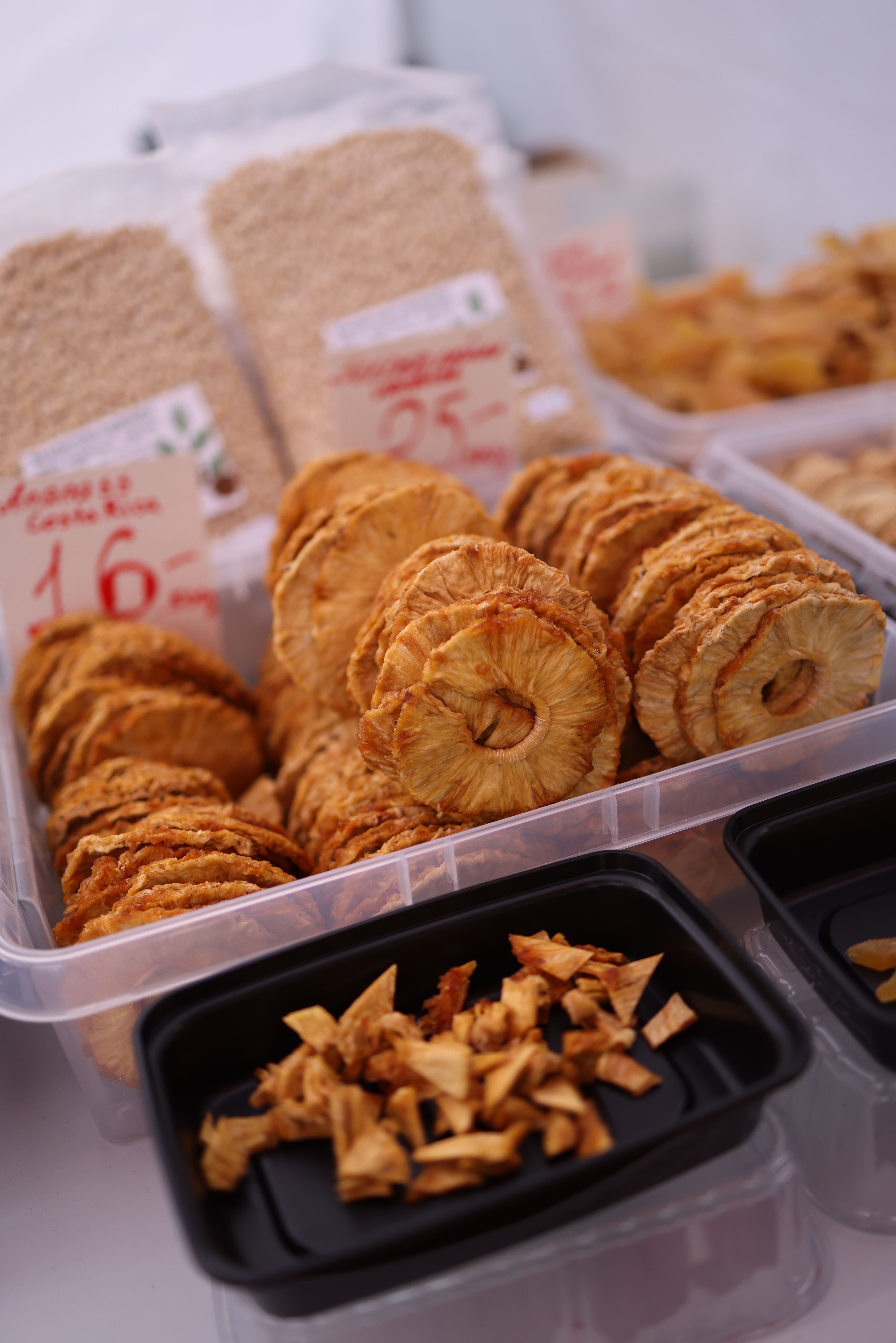 Close-up of dried pineapple rings and snacks at a market stall in plastic containers. - Best Practices for Buying Dry Fruits Online
