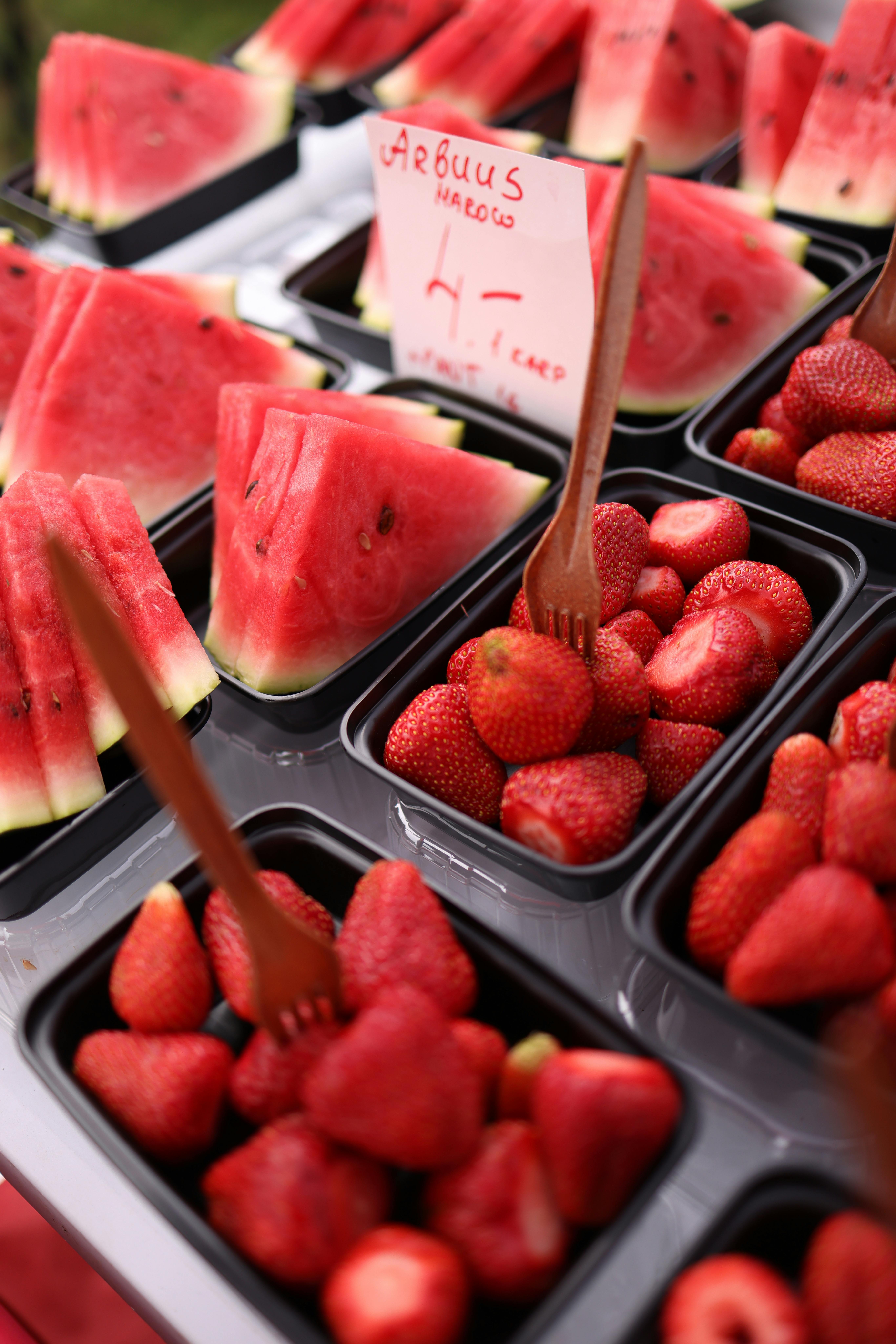 Close-up of vibrant strawberries and watermelon slices at a market stall.