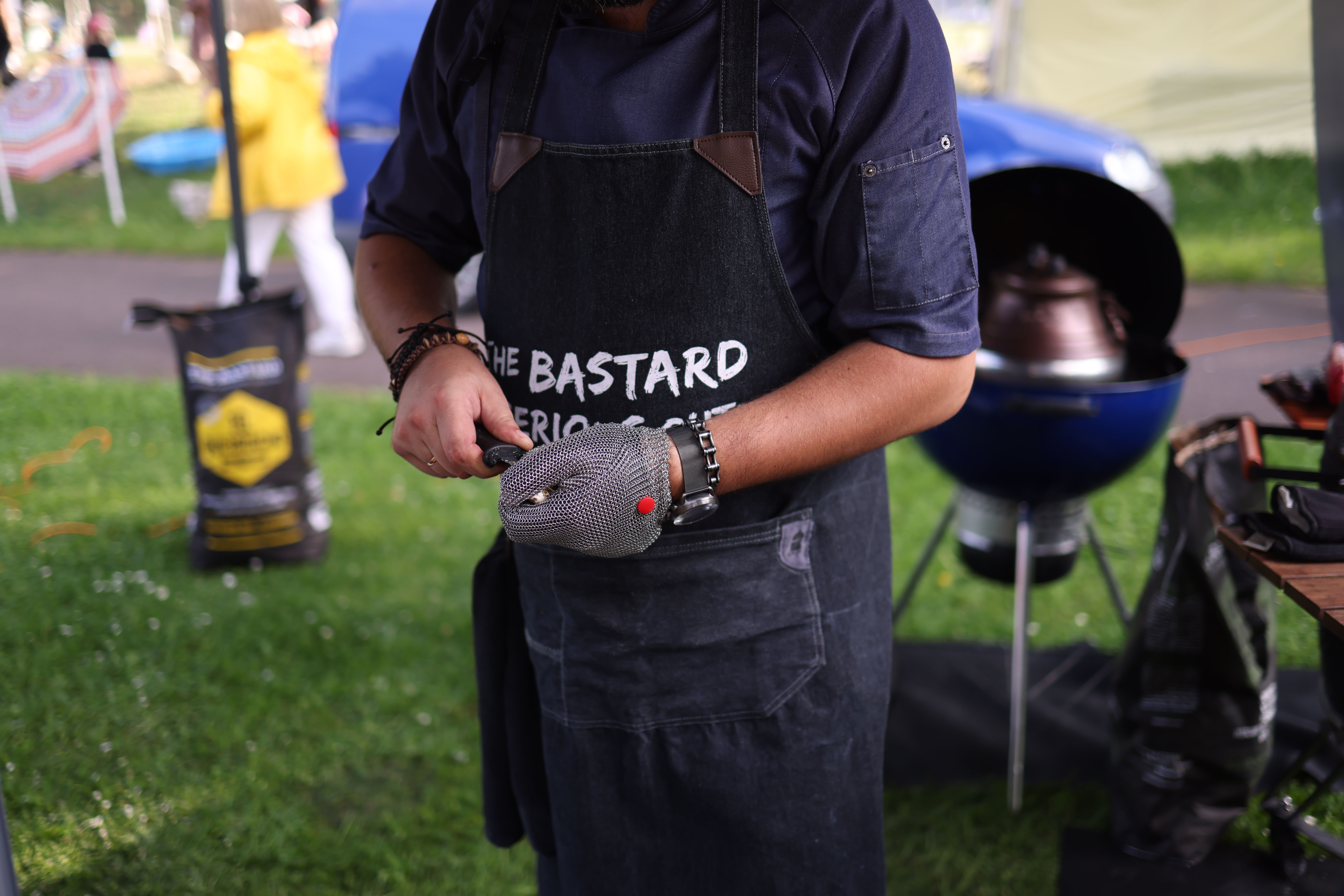 Homme portant un tablier de barbecue en cuir devant un grill allumé
