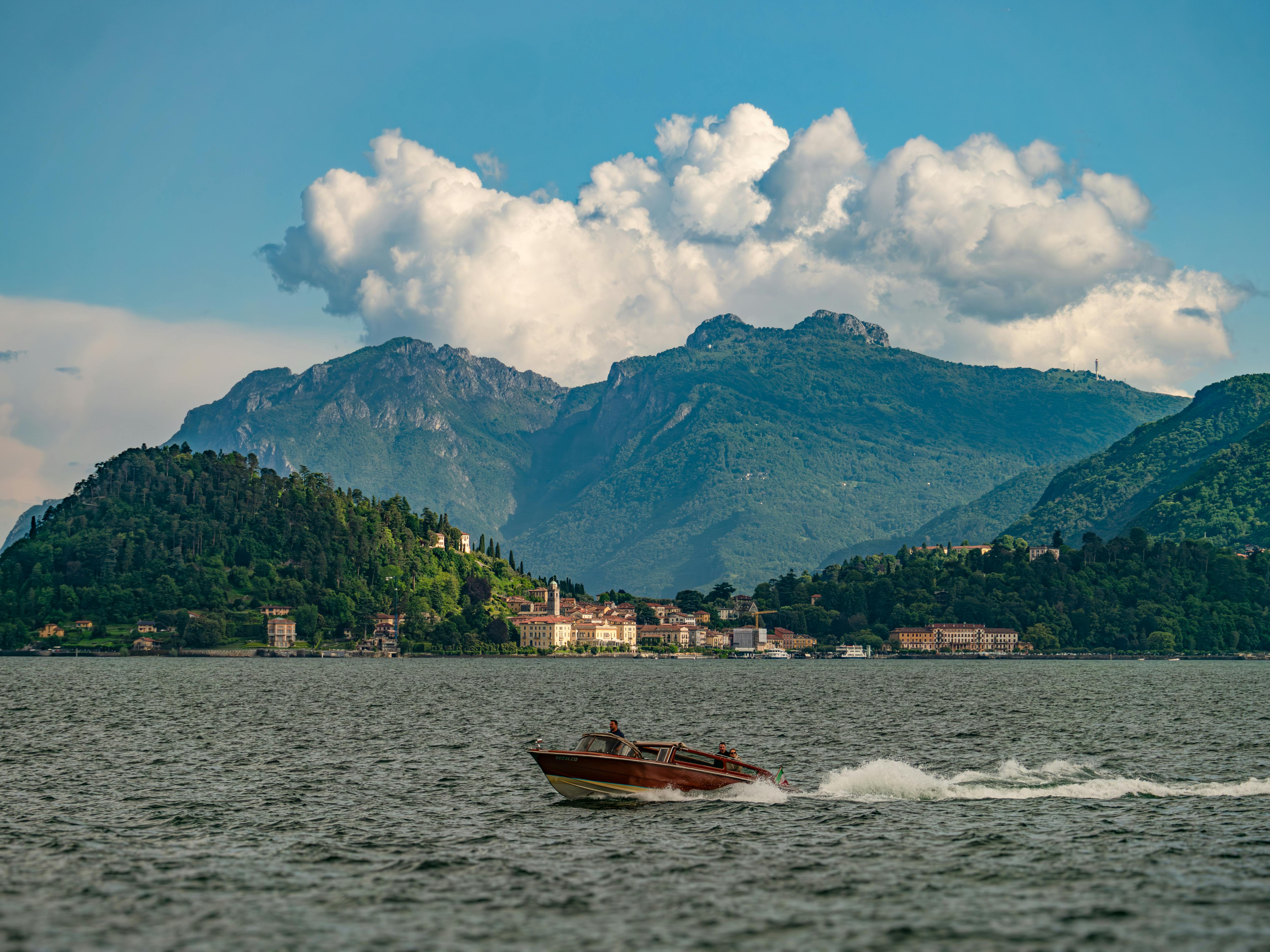 Motorboat cruising on Lake Como with mountain backdrop and Menaggio in view.
