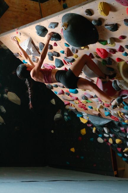 Female athlete demonstrating strength and technique on an indoor climbing wall.