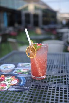 Chilled citrus cocktail garnished with lemon slice and mint on an outdoor café table.