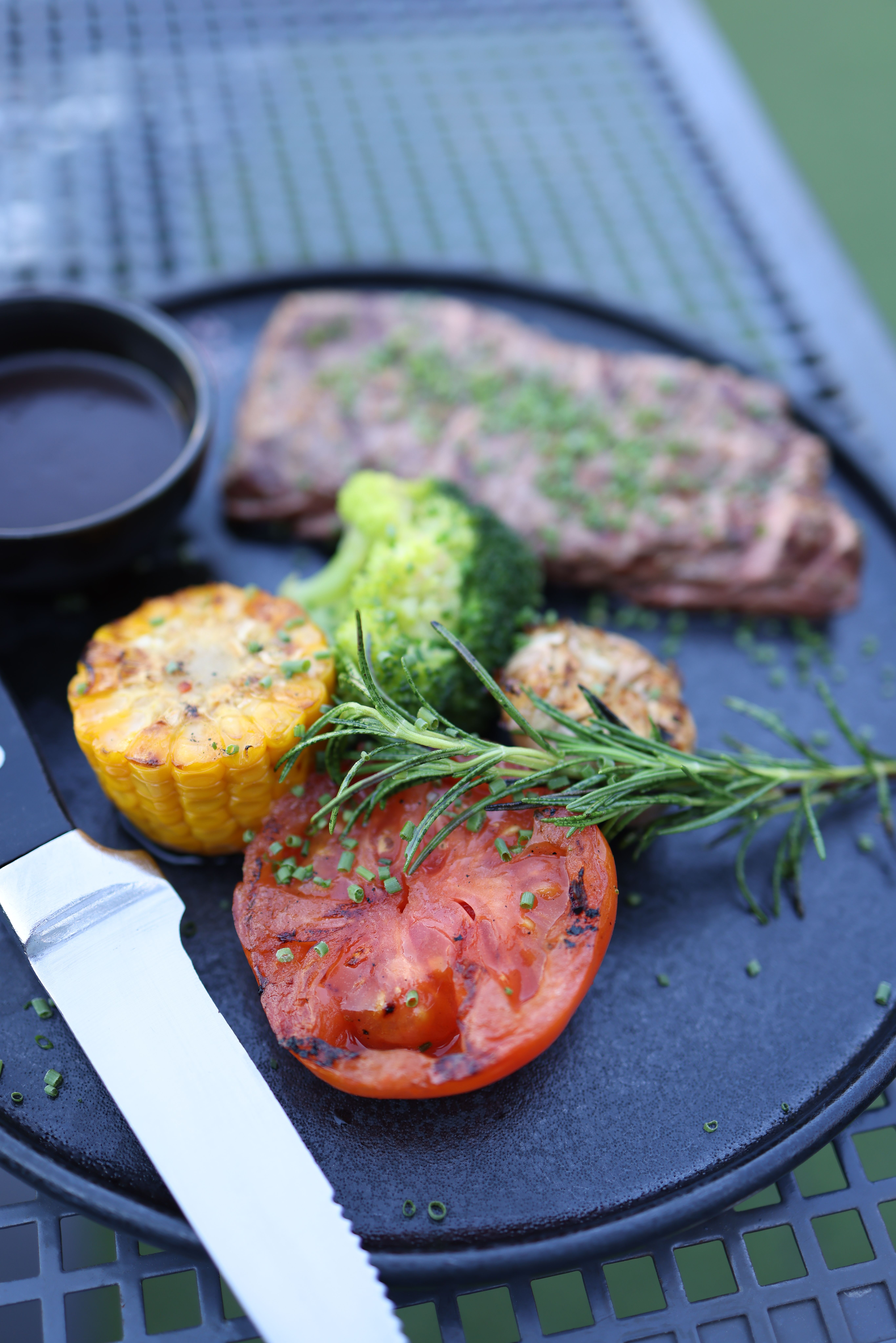 Delicious grilled steak and vegetables with fresh herbs on a plate, ideal for a gourmet meal.